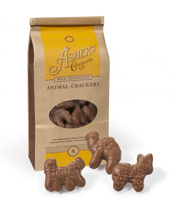 Milk Chocolate Animal Crackers Coffee Bag. Brown Coffee Bag has yellow artwork. Clear plastic circular window on front displays Milk Chocolate Animal Crackers inside. Three (3) Milk Chocolate Animal Crackers are scattered outside of bag to reveal size, shape, color, and texture.